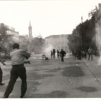 Un momento degli scontri fra forze dell'ordine e dimostranti in piazza della Vittoria il 7 luglio 1960 presso il teatro Romolo Valli, sulla sinistra. Sullo sfondo il teatro Ariosto. Successivamente parte della piazza verrà intitolata ai cinque dimostranti uccisi quel giorno dalla polizia